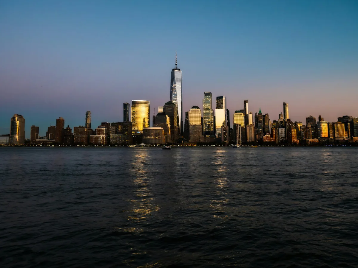 The Manhattan skyline and One World Trade Center at blue hour, seen across the Hudson River